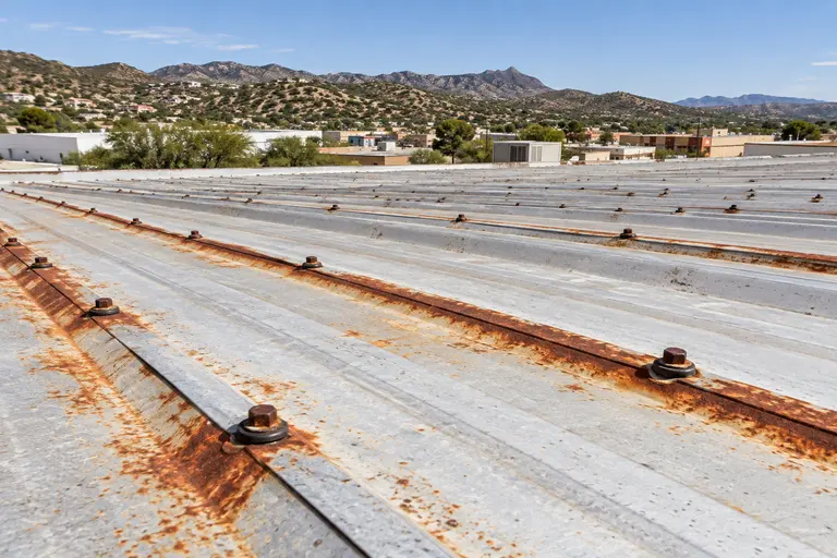 Rust bloom along fastener heads and a panel lap on a commercial metal roof